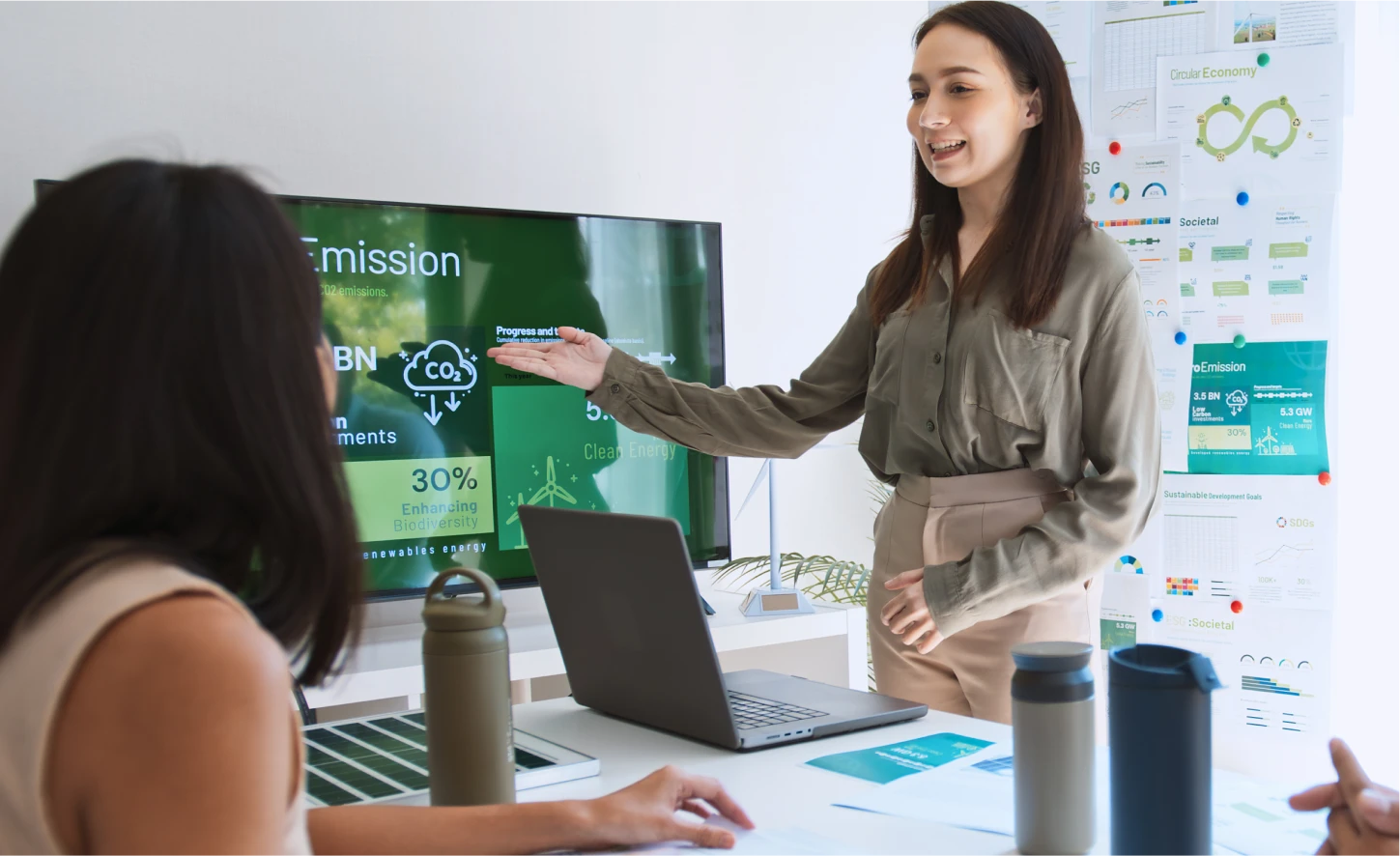 Young woman presents a sustainability report with graphs on a digital screen