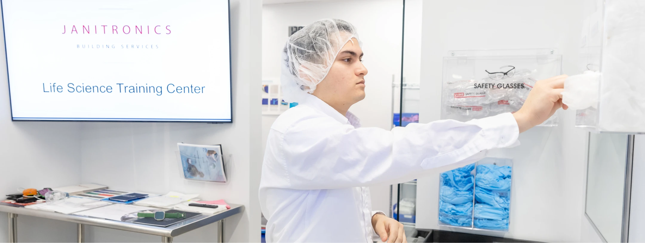Cleanroom technician retrieving disposable gloves from a safety equipment dispenser
