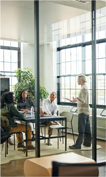 Professional team engaged in a discussion inside a modern office meeting room with large windows