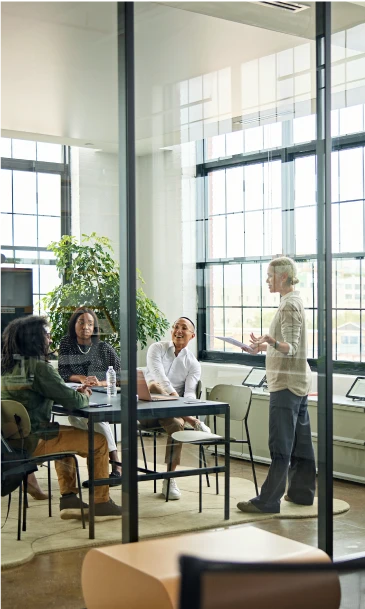Business meeting in a bright glass-walled office with team members engaged in discussion