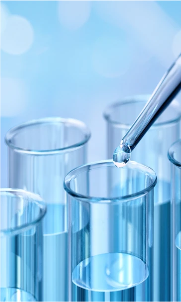 Laboratory pipette dispensing a liquid drop into a clear test tube with a blue background