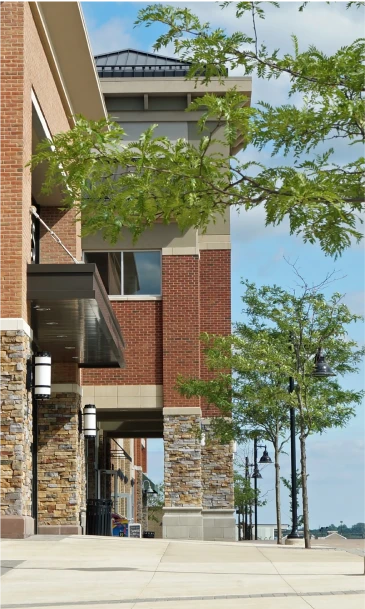 Contemporary retail plaza featuring brick architecture, stone columns, and lush greenery