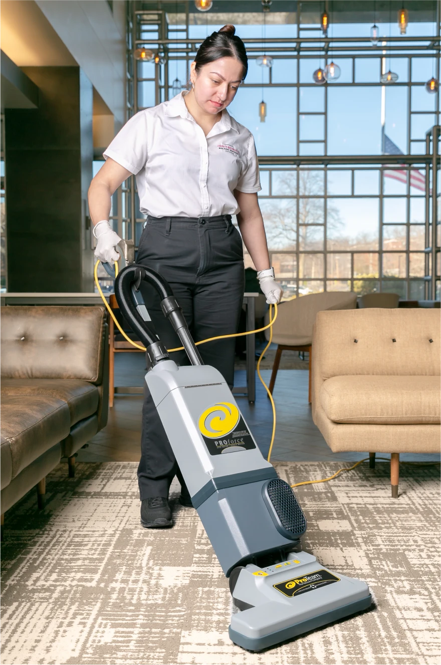 Janitronics employee vacuuming a modern lounge area with a commercial-grade vacuum cleaner