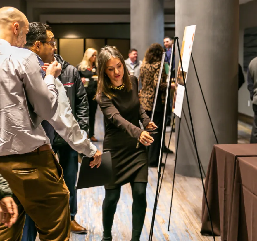 Engaged attendees examining details on an easel display during a business event