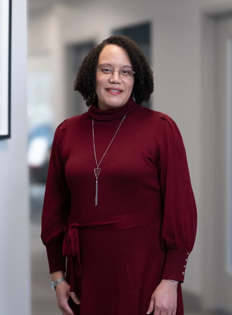 Smiling businesswoman wearing stylish burgundy sweater dress and glasses in office environment