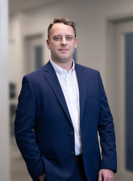 Confident business professional in navy blue suit posing in hallway with composed expression
