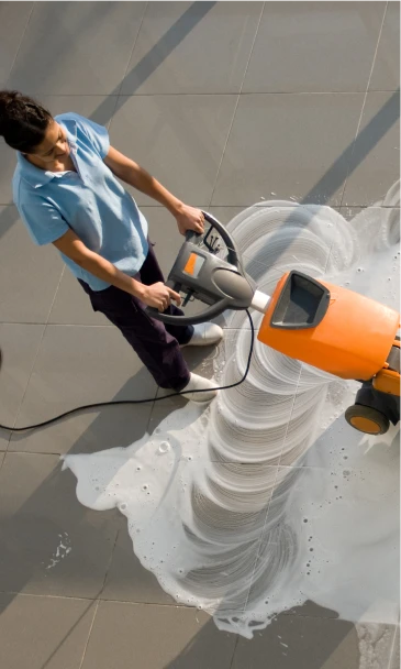 Cleaning professional using a floor scrubber machine to deep clean a tiled surface