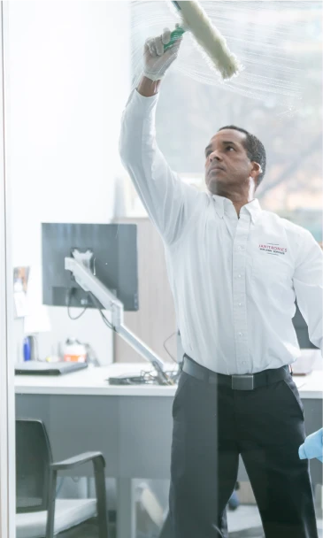 Office cleaning professional using a squeegee to clean a glass window in a workplace setting