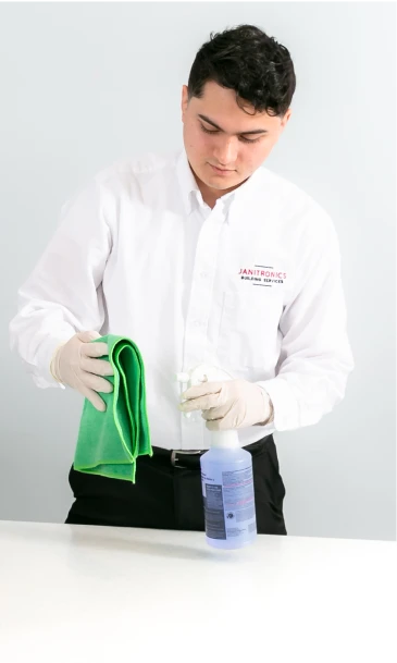 Janitorial worker using a green microfiber cloth to sanitize a countertop