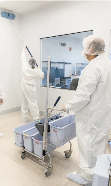 Workers in full PPE cleaning a controlled lab facility with specialized equipment