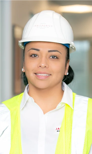 Smiling female professional wearing a white hard hat and high-visibility safety vest