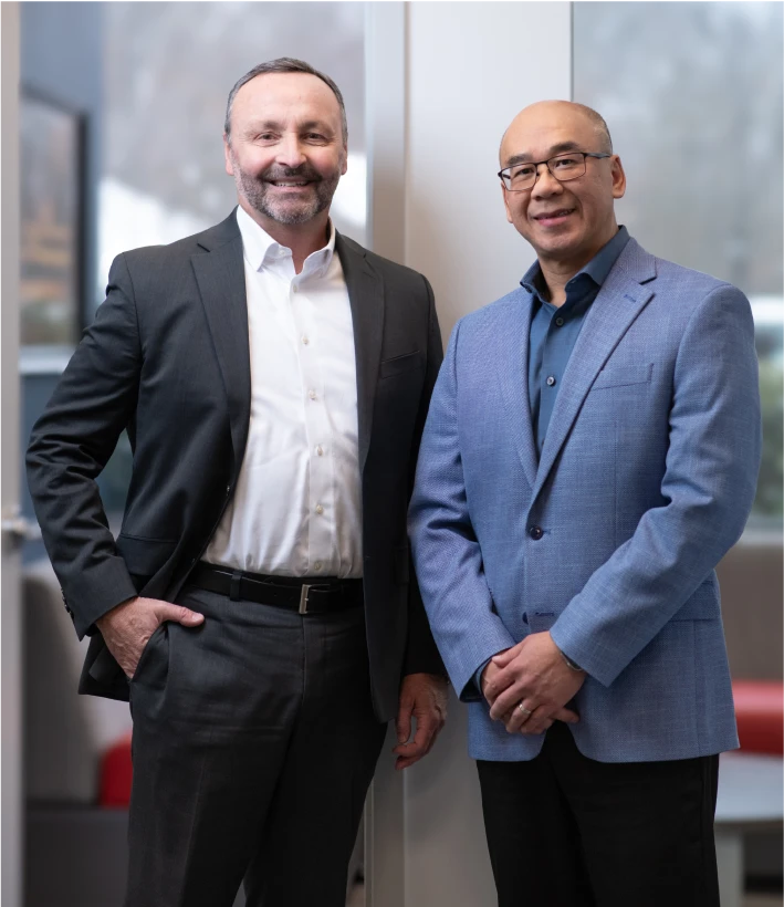 Smiling corporate leaders dressed in formal attire standing in a modern workspace