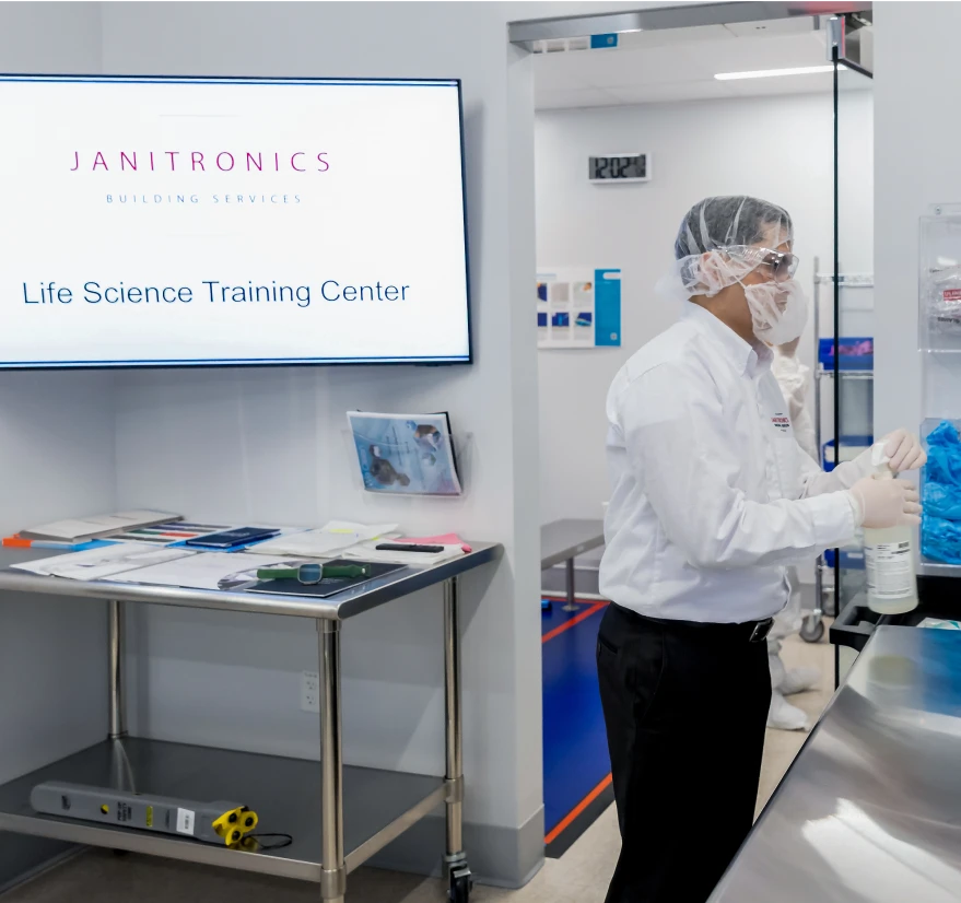 Janitronics Life Science Training Center employee in protective gear disinfecting a cleanroom workspace