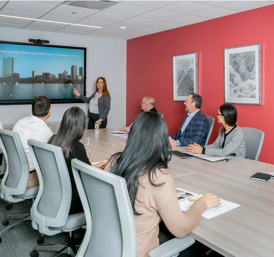 Businesswoman giving a presentation to a team in a modern conference room with red walls