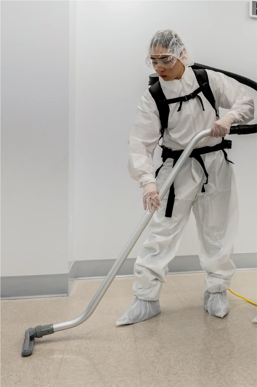 Lab worker in a hazmat suit using a commercial vacuum in a sterile facility